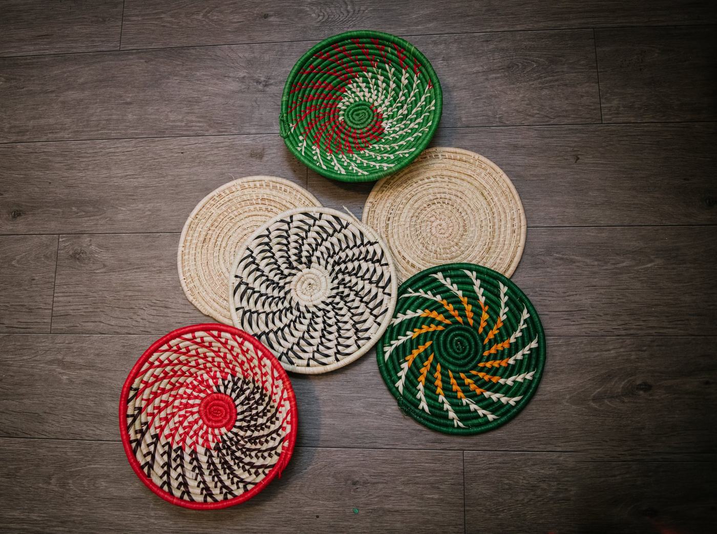 Six woven raffia baskets in different color patterns fanned out together