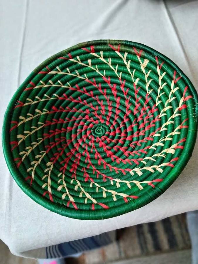 Forest green woven raffia basket with a crimson and cream radiating pattern