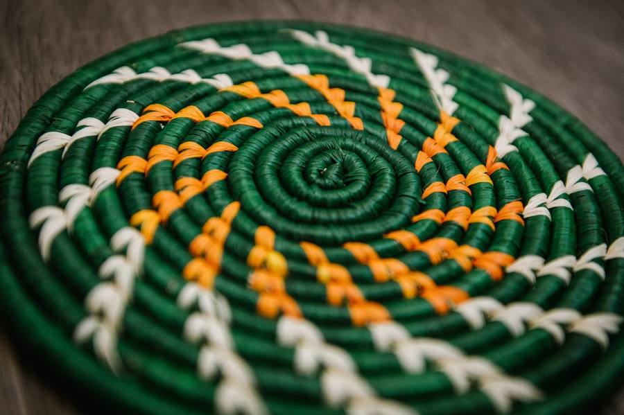 Forest green woven trivet with a marigold and cream spiral pattern