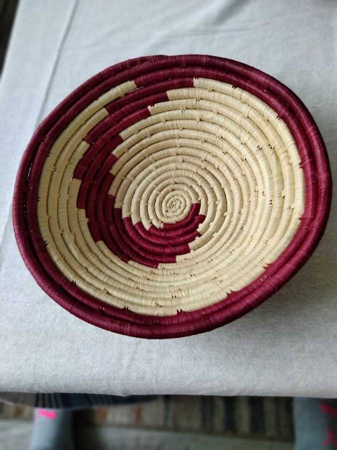 Maroon and cream woven raffia bowl with spiral pattern