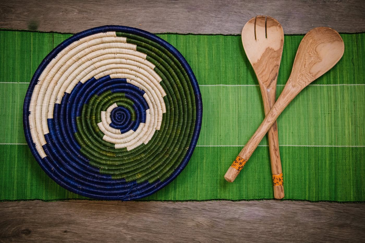 A woven indigo and olive basket paired with hand-carved wooden salad servers