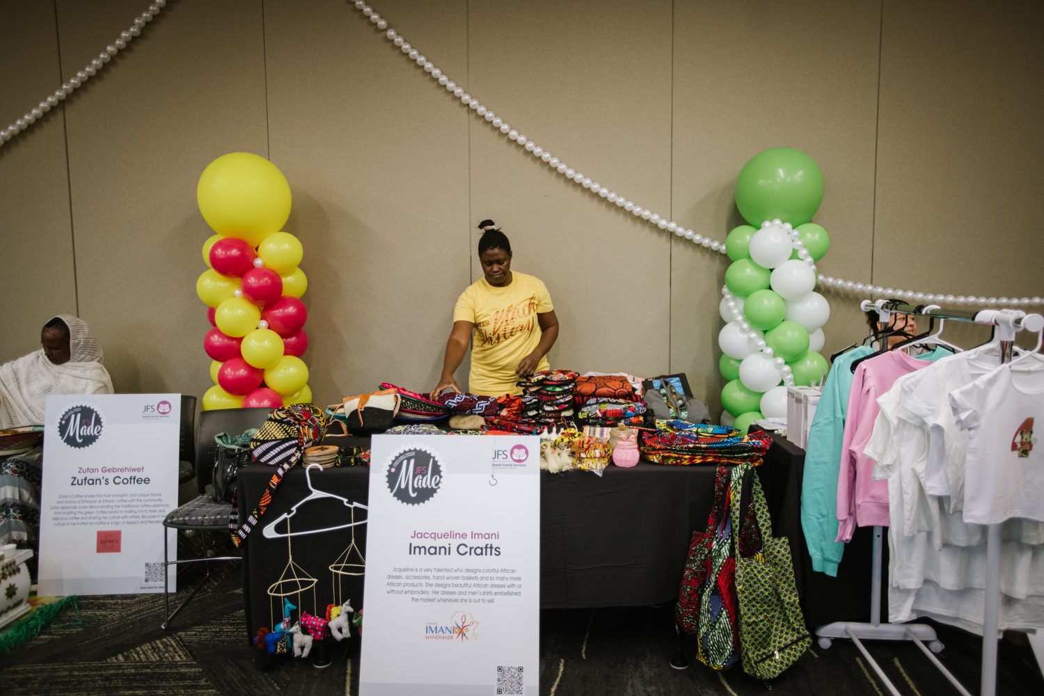 Jacqueline Imani at her JFS MADE vendor table, arranging Ankara scarves and bags
