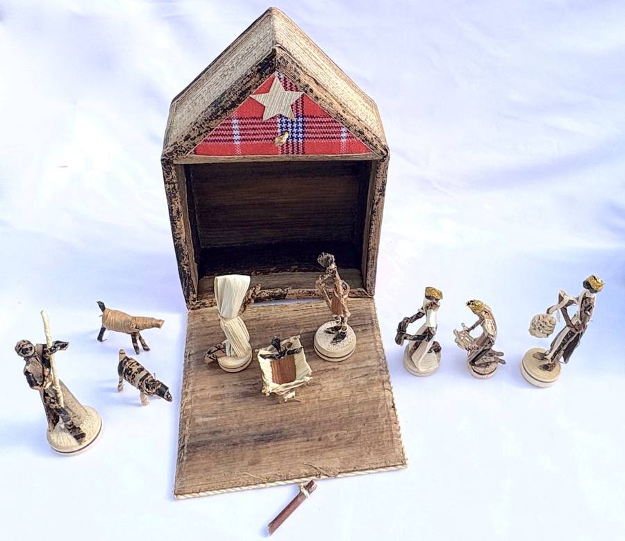 A miniature nativity set with figures and a stable crafted from natural raffia and wood