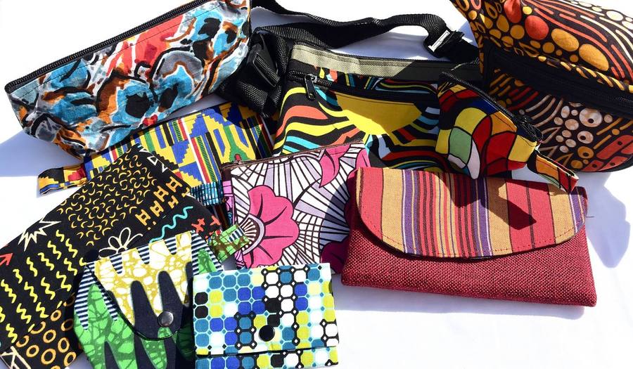 An assortment of wax-print fanny packs, pouches, and clutches in mixed prints
