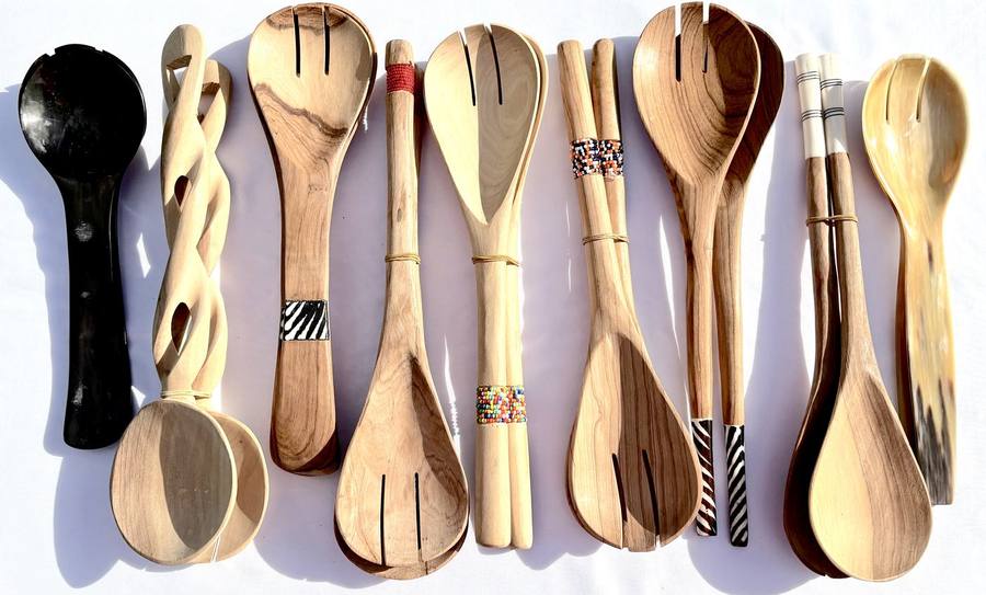 An assortment of hand-carved wooden serving spoons and forks with horn, beaded, and painted handles
